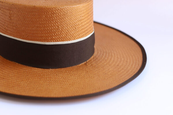 Sombrero marrón con cinta negra y detalle blanco.
